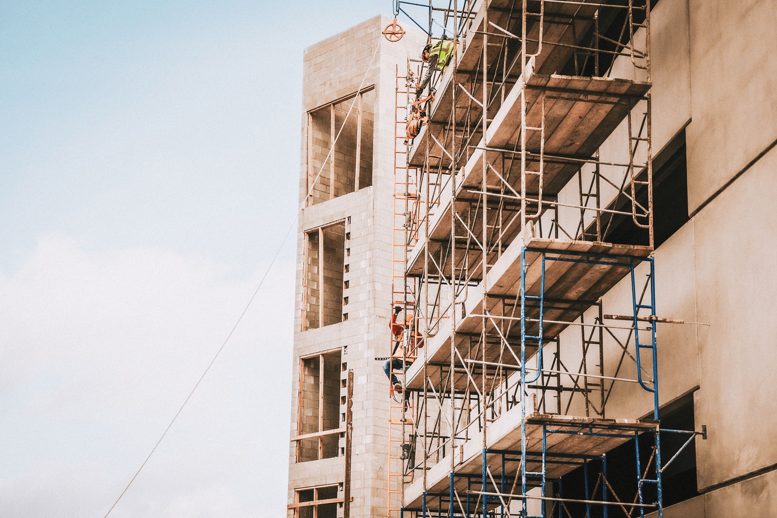 The image depicts a construction site with a partially completed multi-story building. The building ...