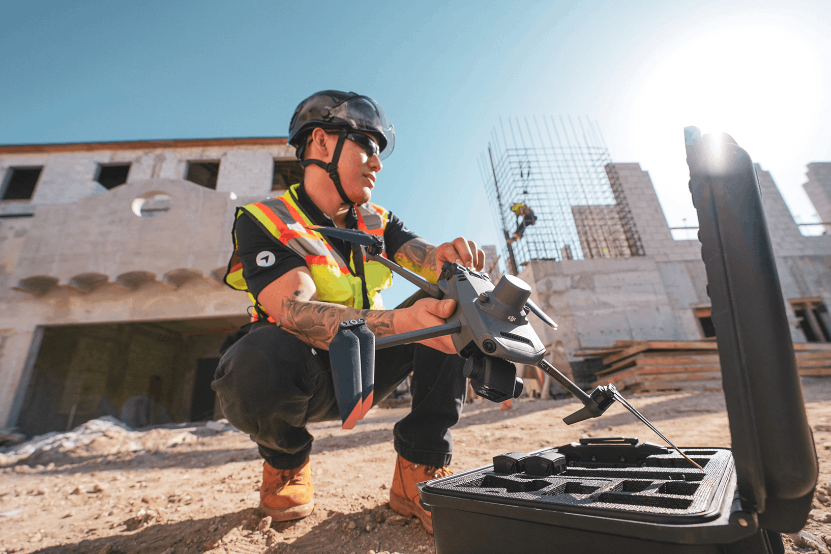 A construction worker wearing a hard hat, safety vest, and protective gear is operating a power tool...