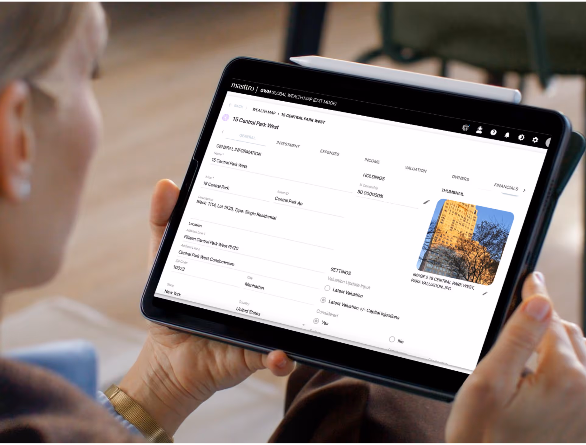 Person holding a tablet displaying a property management interface for 15 Central Park West with details and a building photo thumbnail.