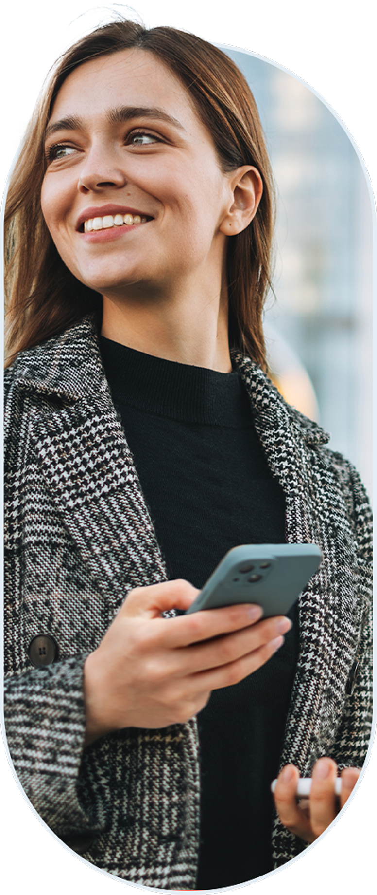 Smiling woman holding a smartphone outdoors.