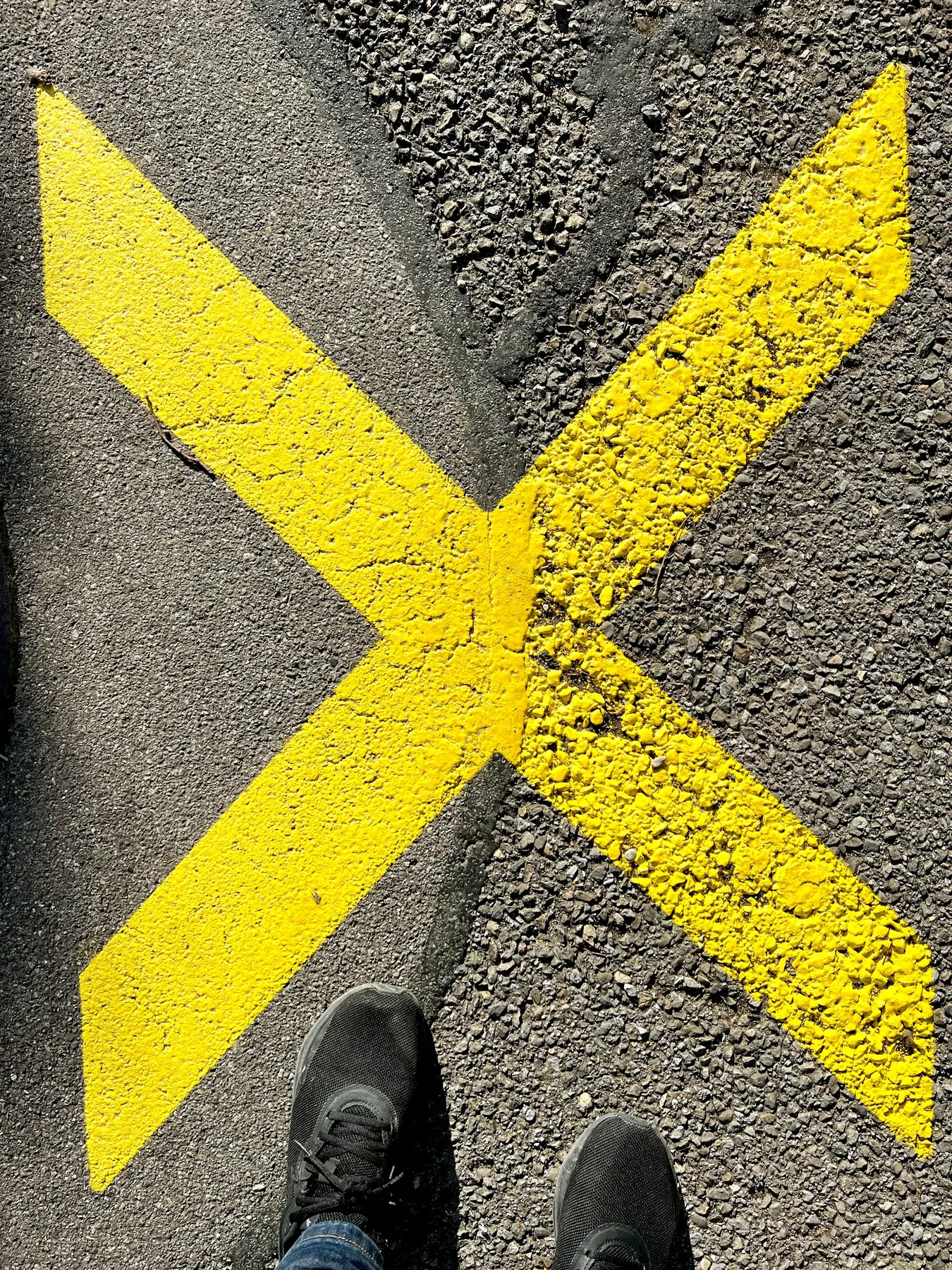 Gelbes Kreuz auf Asphalt – grafisches Fundstück im Alltag