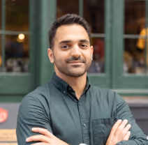 A Hirad Roshandel picture. He is wearing a green shirt, has his arms crossed and is staring at the camera amicably. 