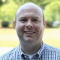 A Scott Byrge picture. He's smiling at the camera wearing a plaid shirt.