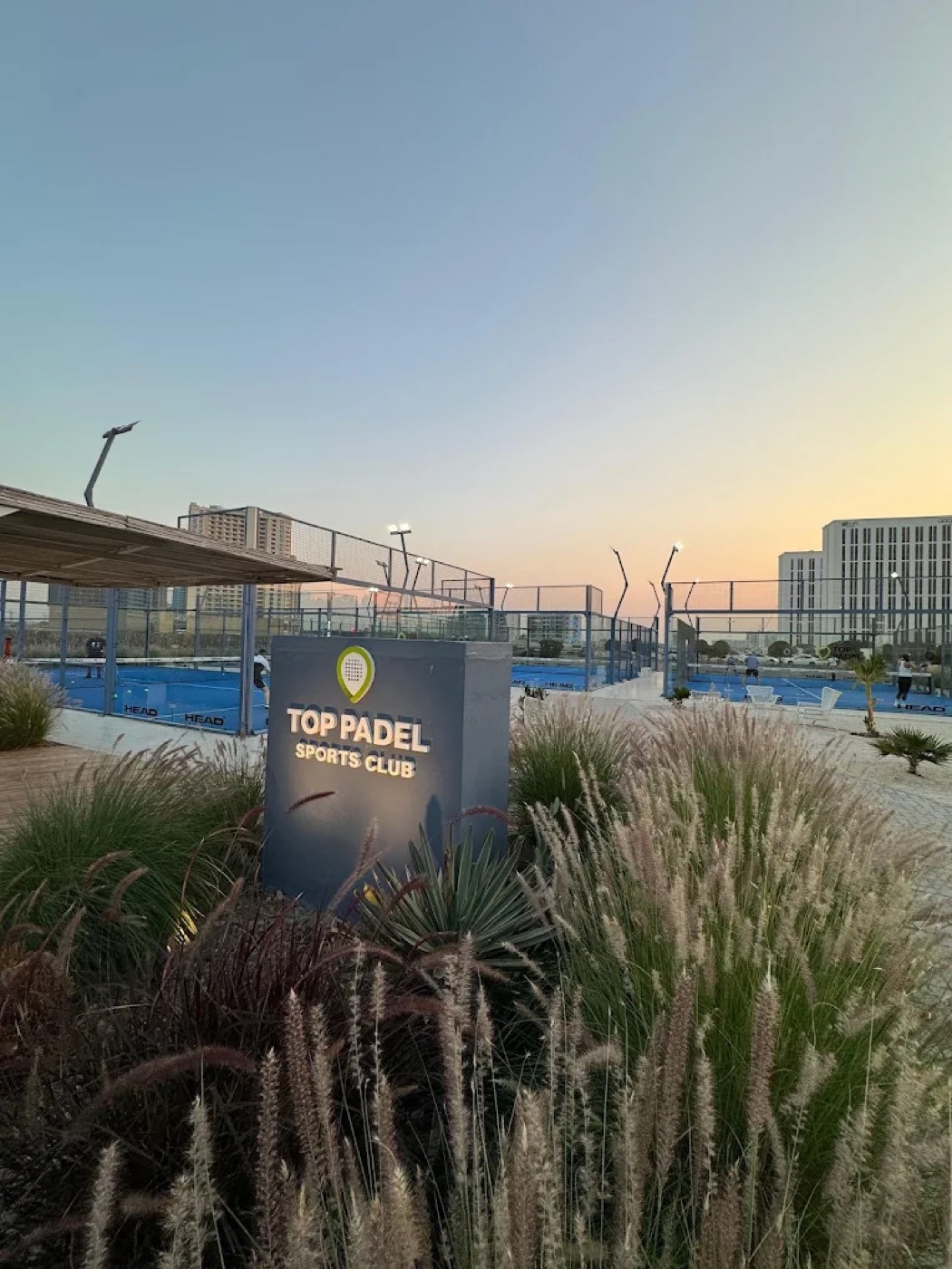 Top Padel Sports Club entrance sign with outdoor padel courts at Me'aisem, Dubai, at sunset