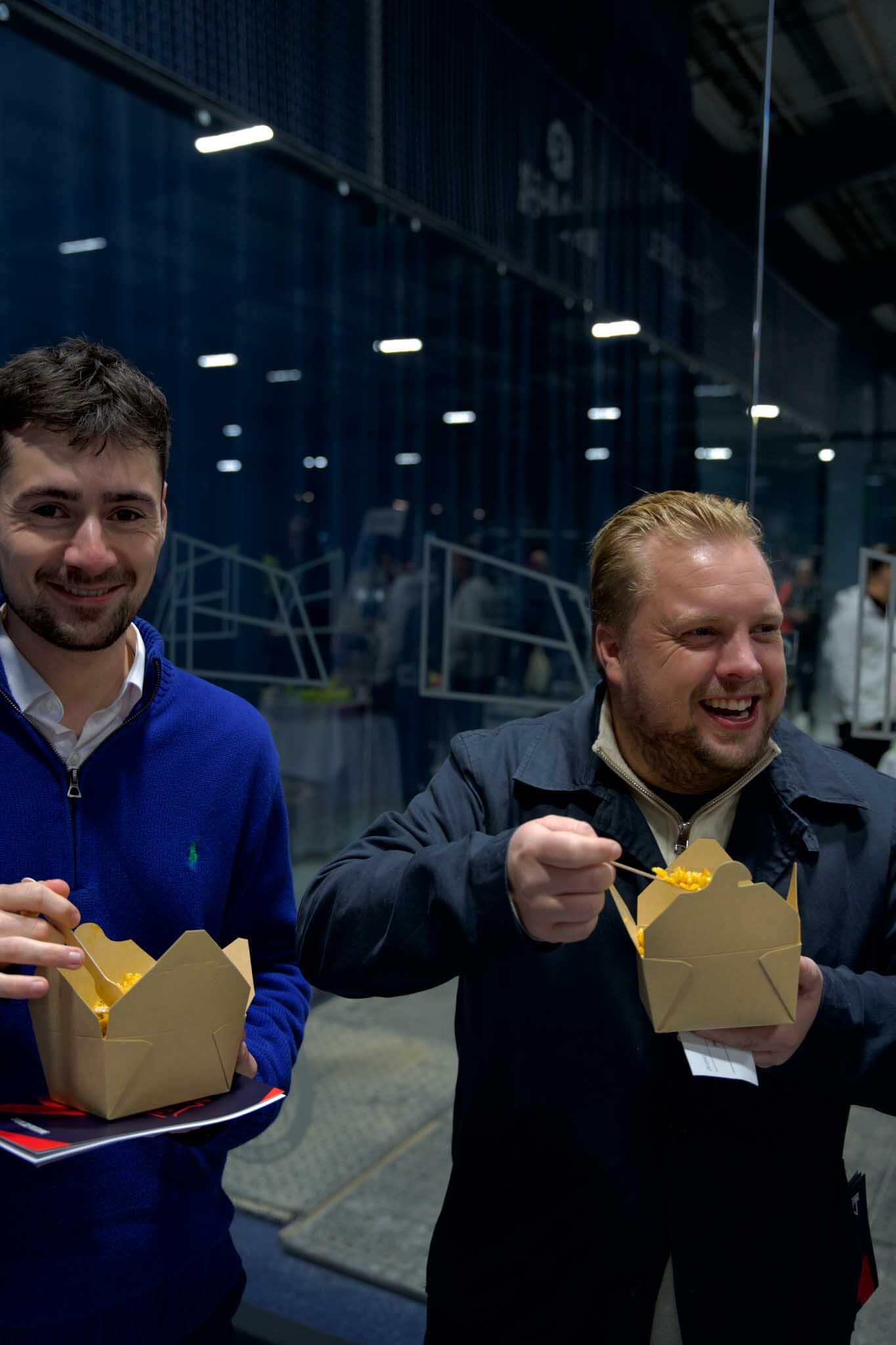 Two man eating paella from the box