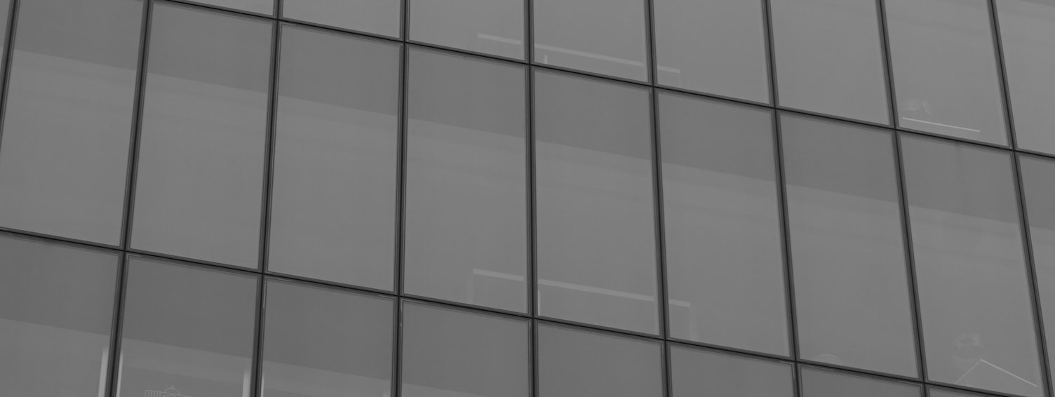 Grey glass office building facade with repeating window panes