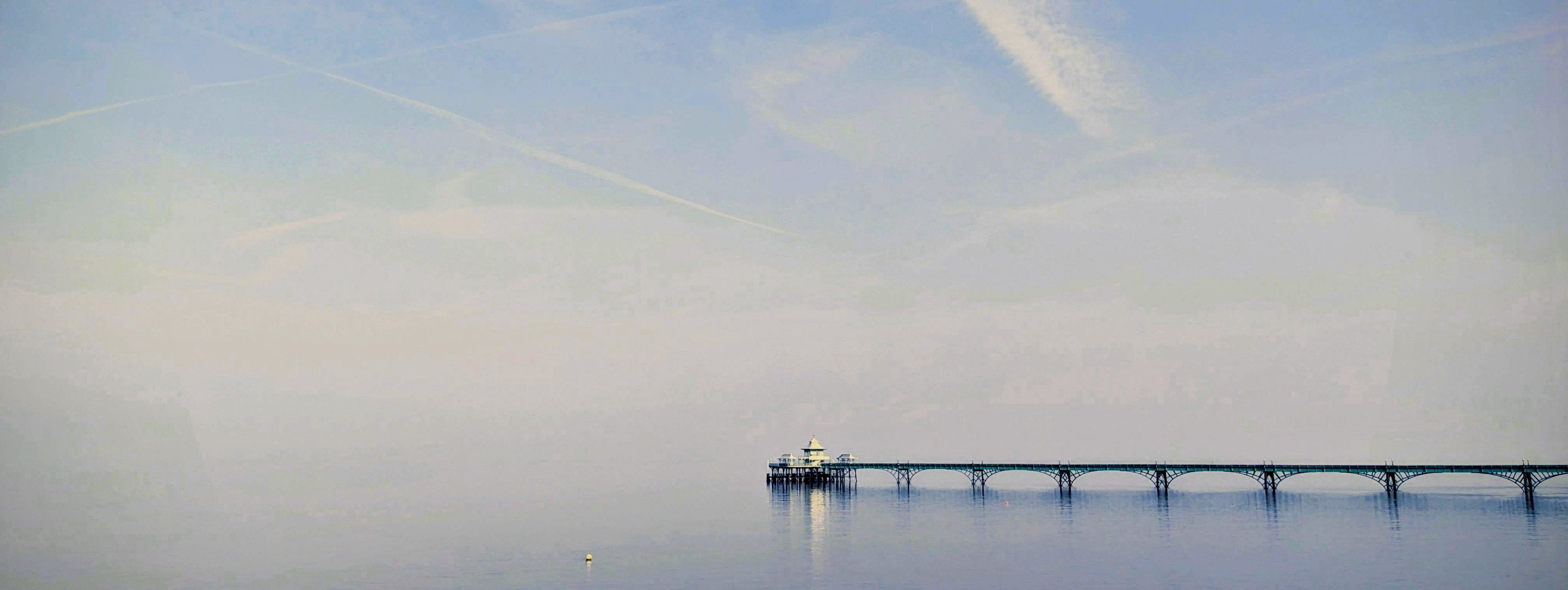 Pier extending into calm water at dusk, photo by John-Mark Strange