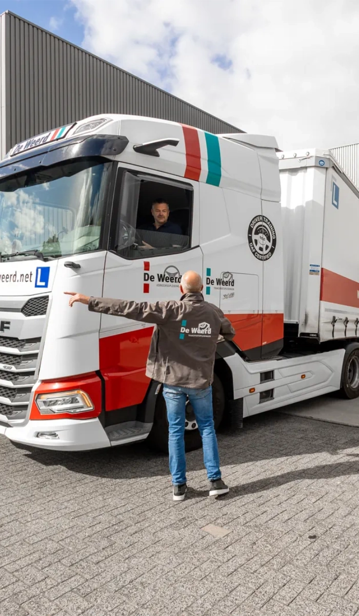 Instructeur van De Weerd Opleidingen geeft aanwijzingen aan een cursist die met een lesvrachtwagen manoeuvreert