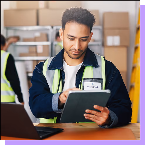 Warehouse worker with clipboard uses laptop