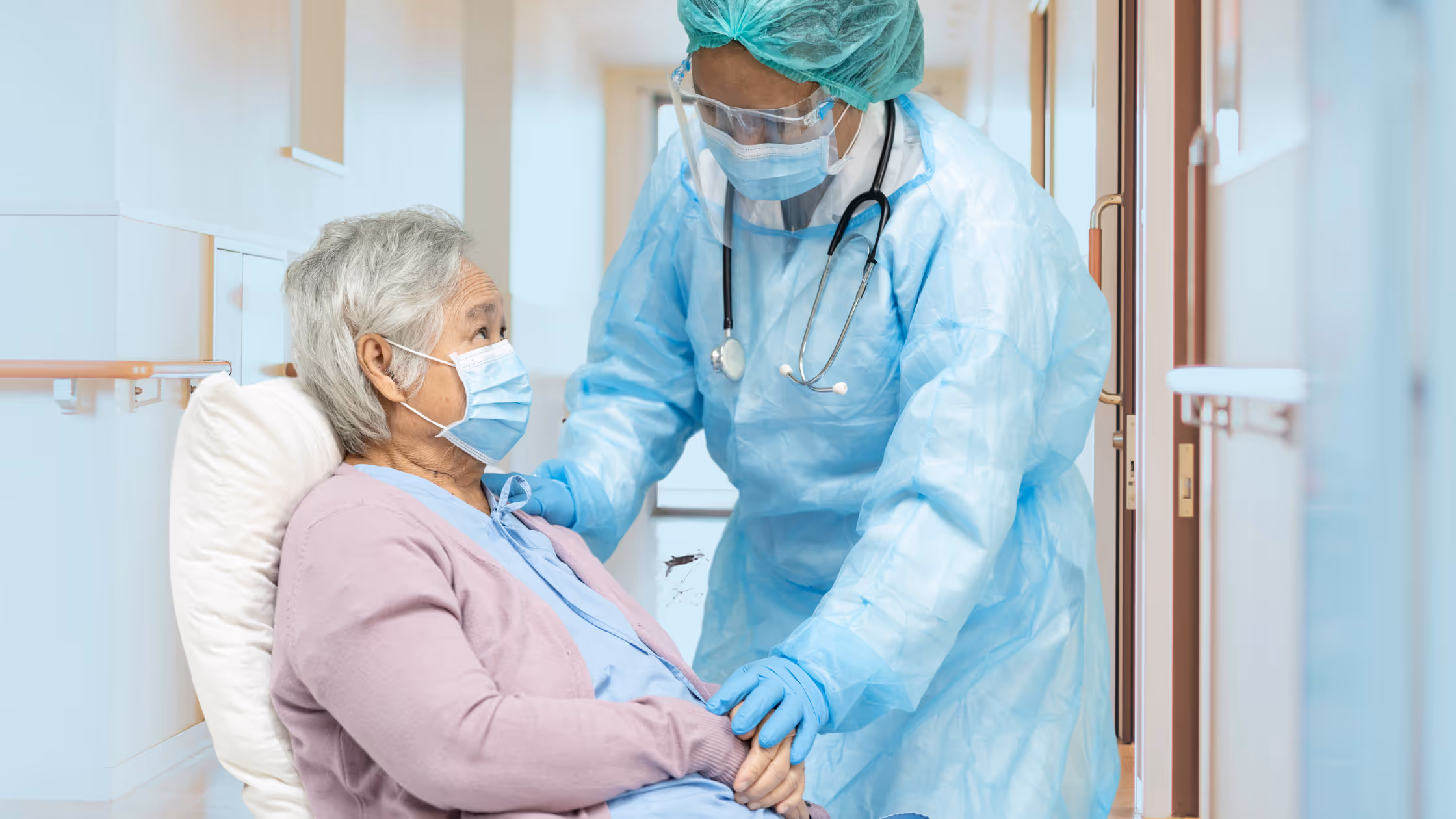 nursing home employee wearing full PPE caring for elderly woman .