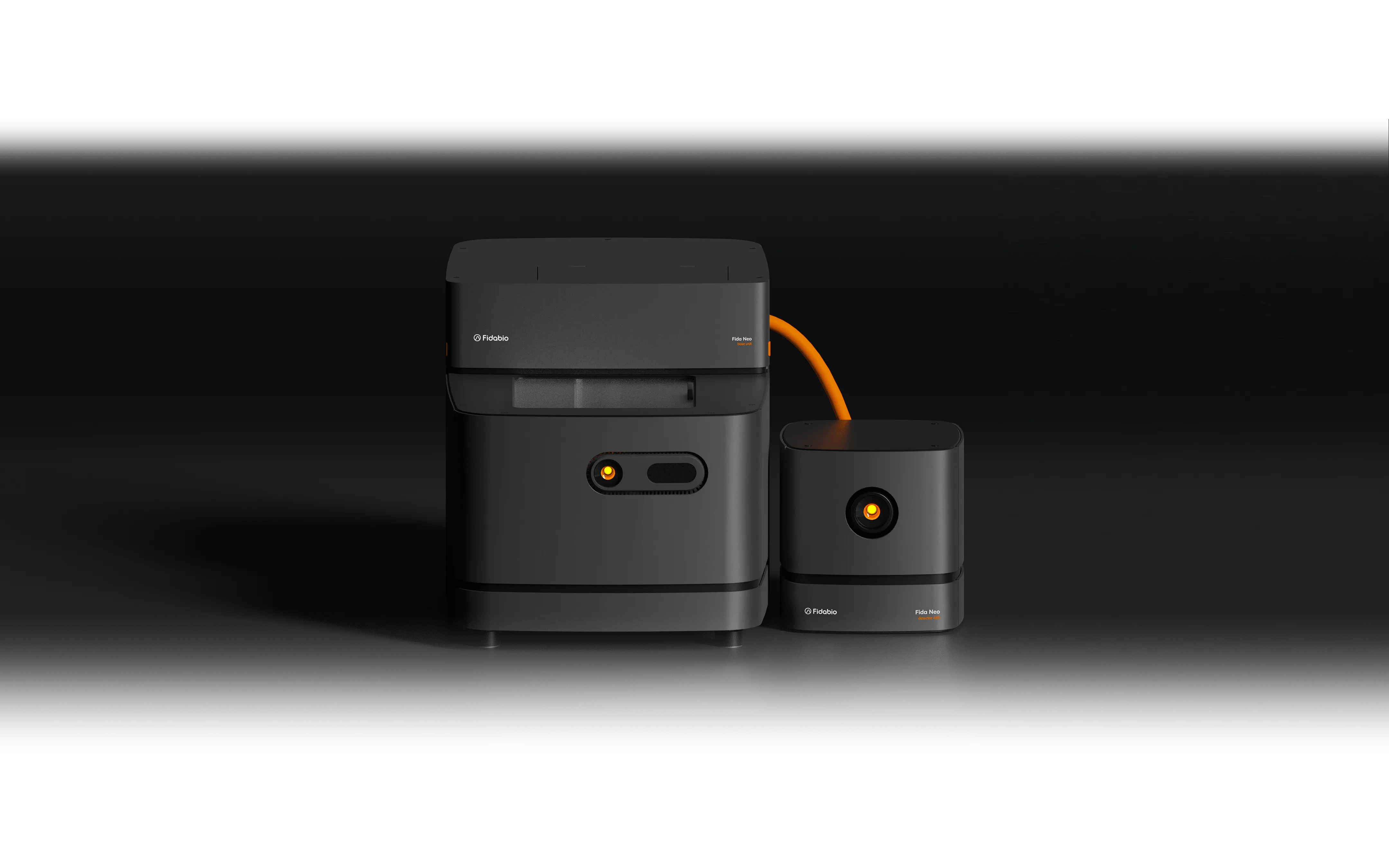 Sleek black medical devices on a dark background. The larger unit is connected to a smaller one with an orange cable, both with orange-lit circular indicators.