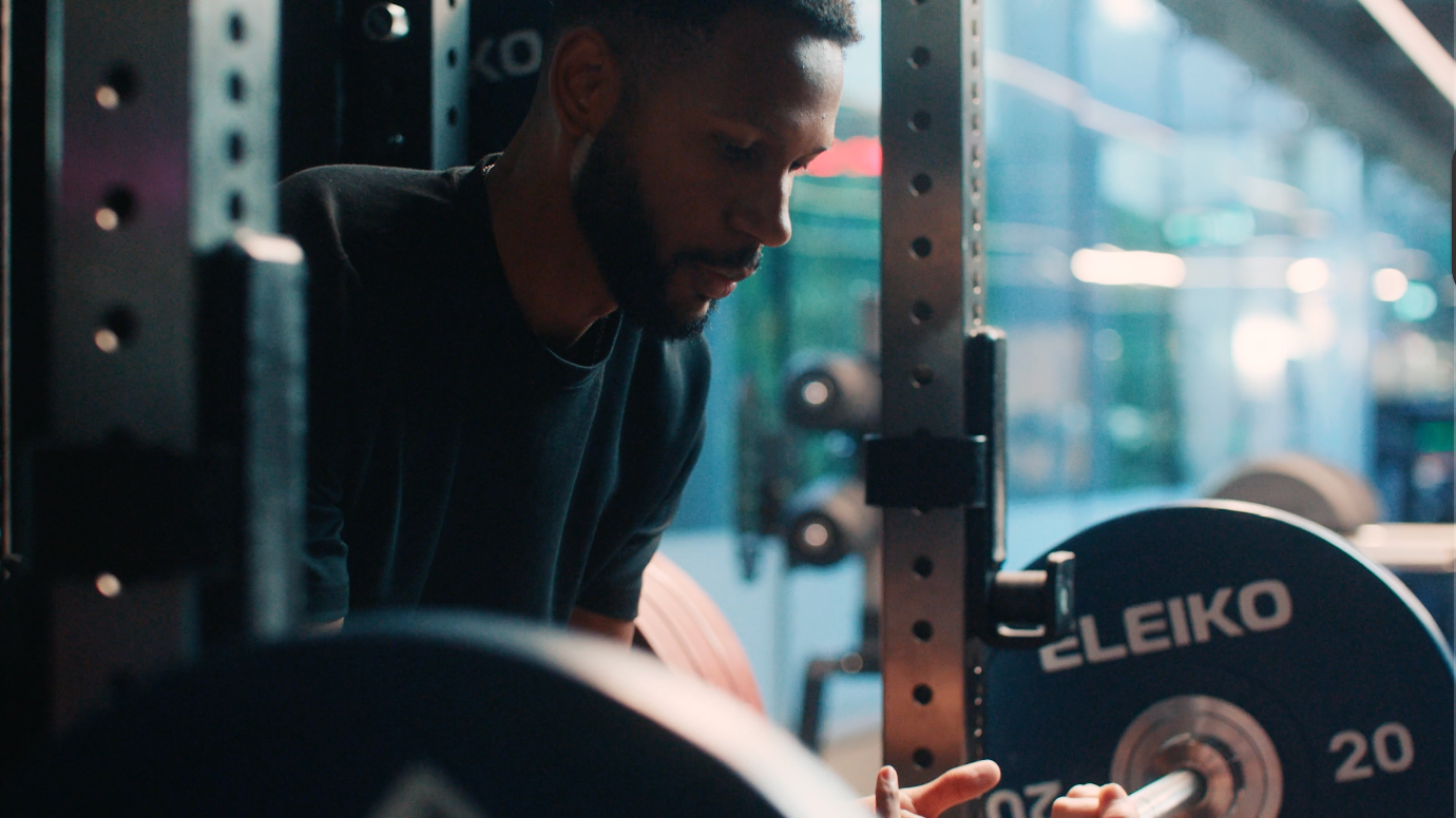 Man adjusting weights on an Eleiko barbell in a gym setting.