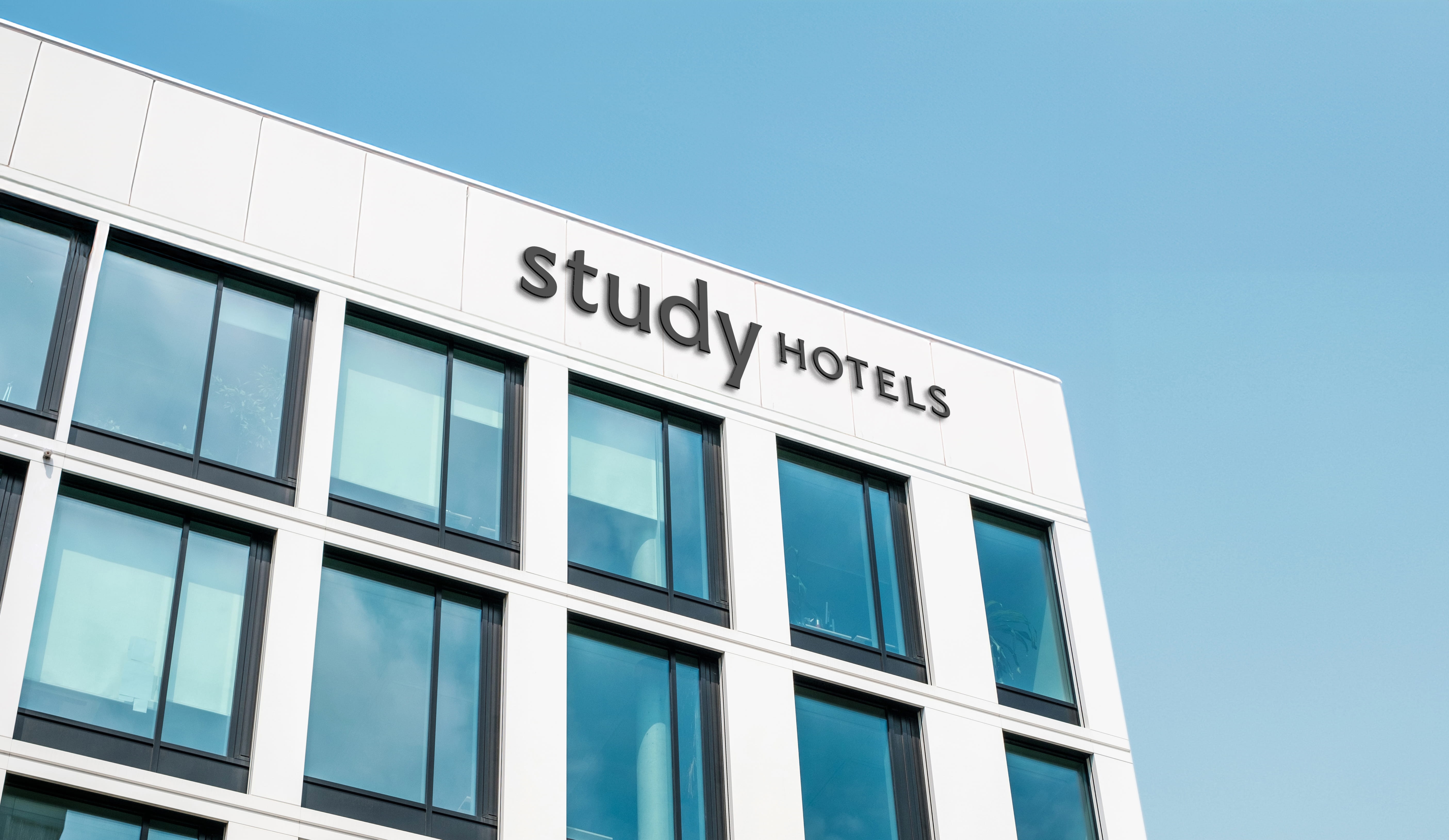 White building captured from below against sky with sign "Study Hotels"