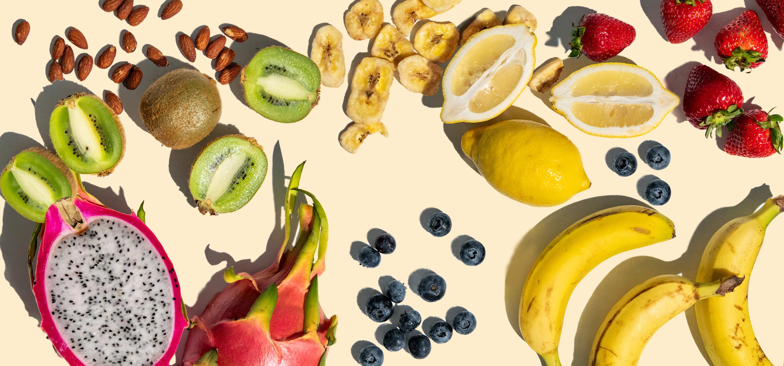 Photograph of various fruits and snacks on a cream background