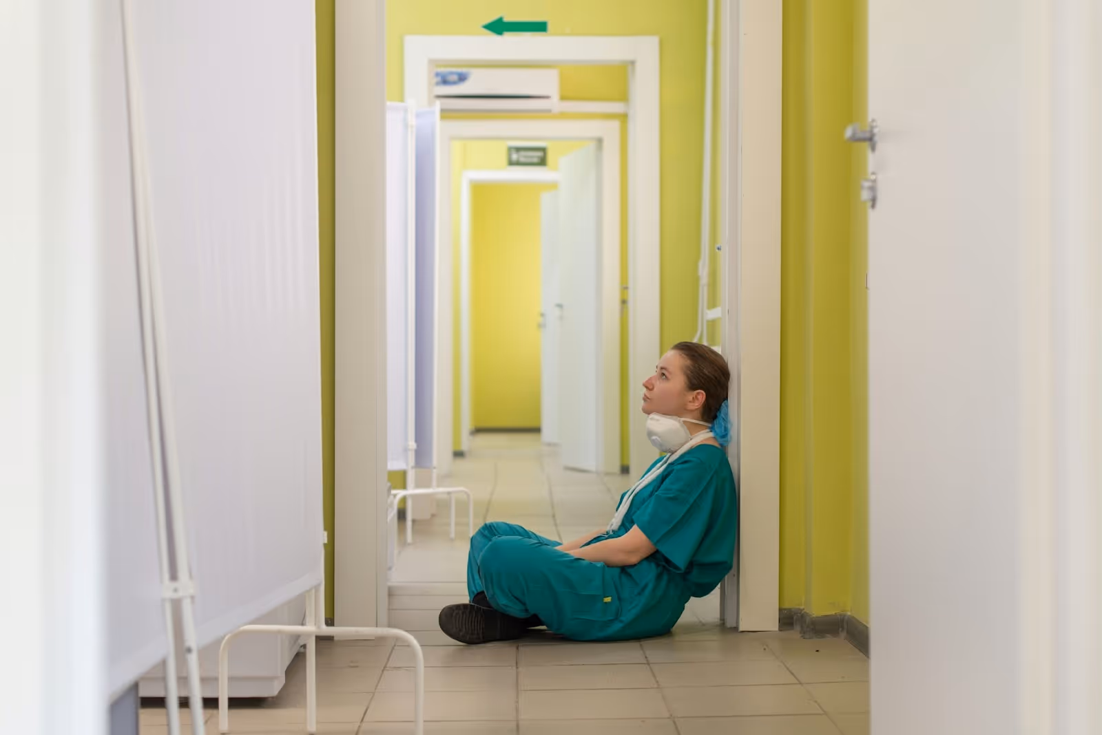 A travel nurse sitting on the floor, feeling the effects of burnout