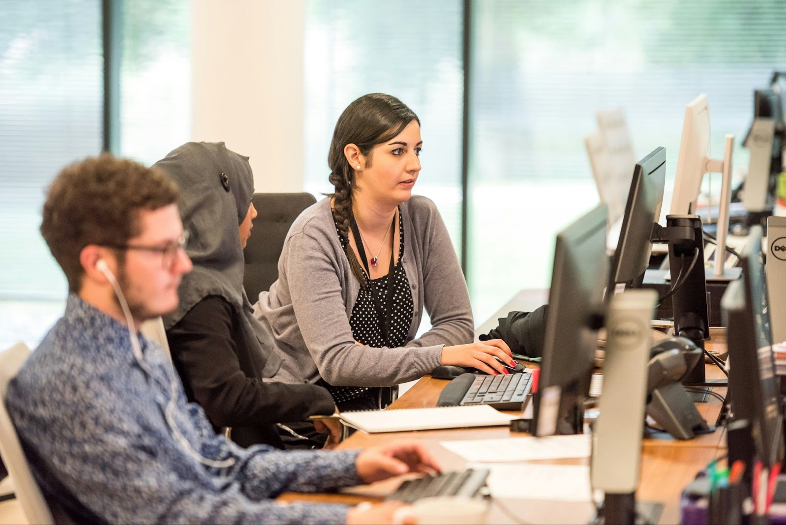 A woman looking a the screen of the computer with her colleagues beside her