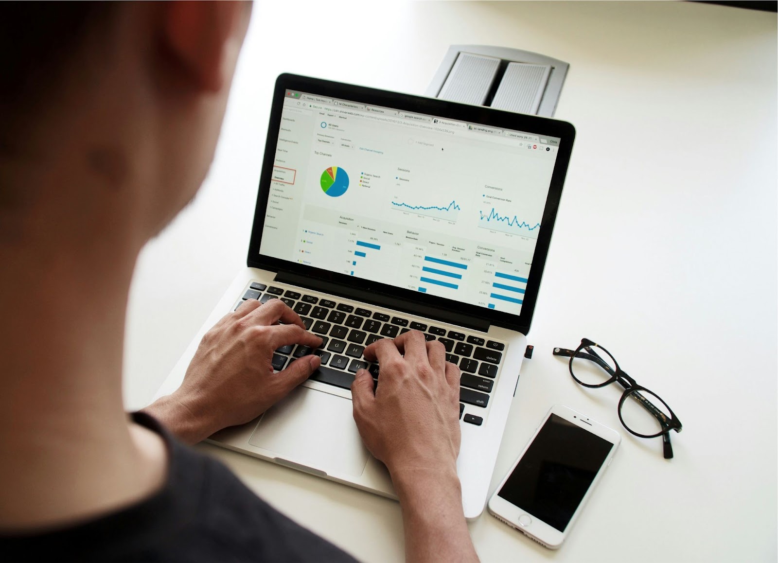 A man looking at a laptop with pie charts and graphs