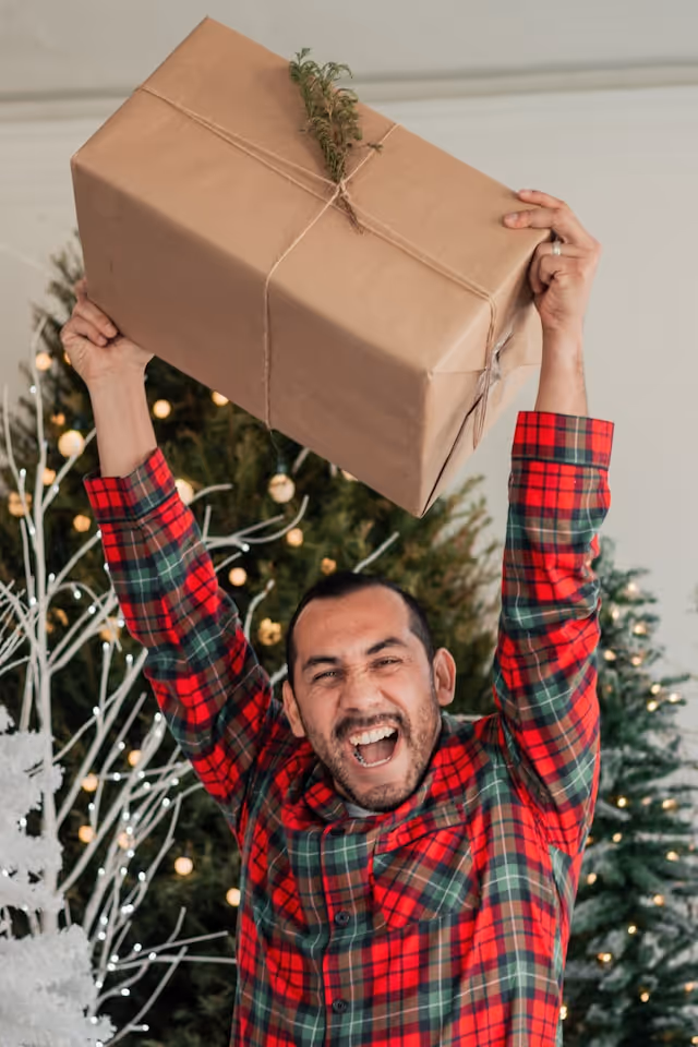 A guy in an ugly sweater in front of a Christmas tree