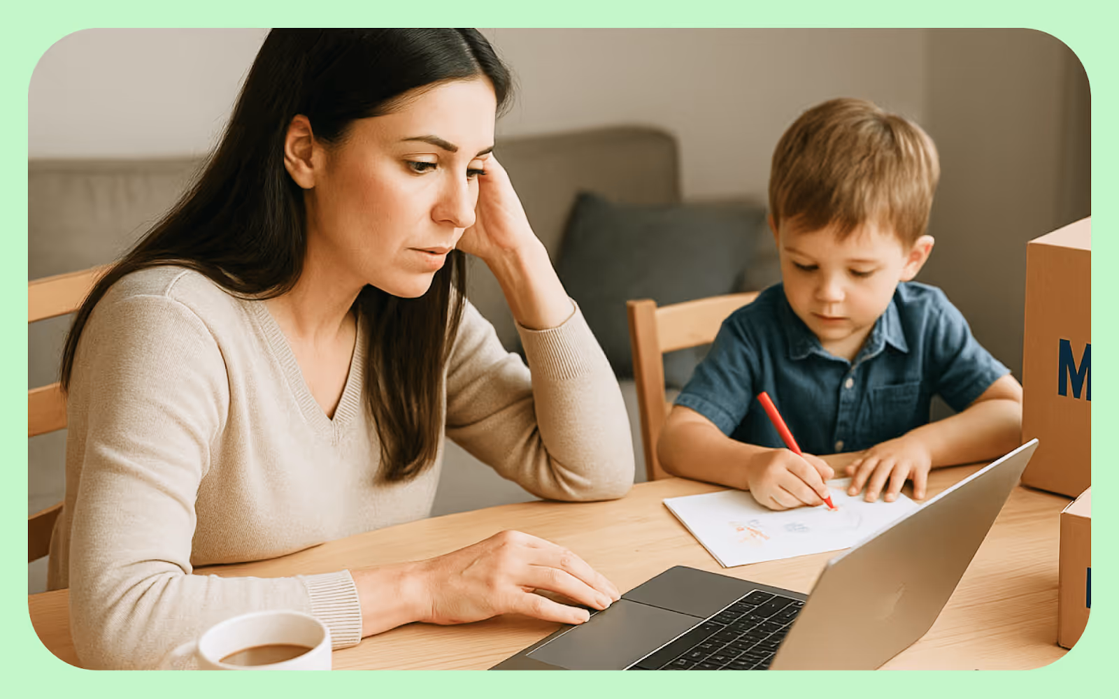 A mother works on her laptop next to where her son is drawing.