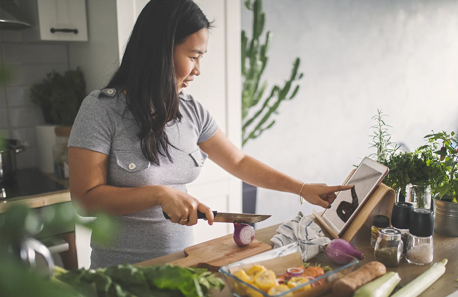 Woman reading from tablet while preparing ingredients