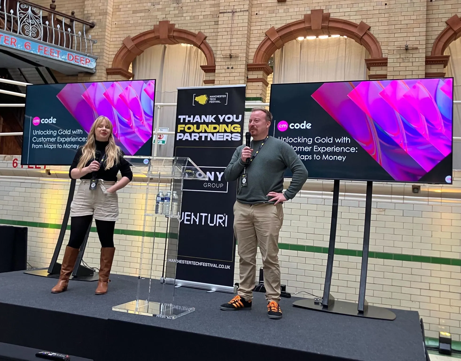 Hero Image of 2 Speakers on Stage Holding Microphones at an Event