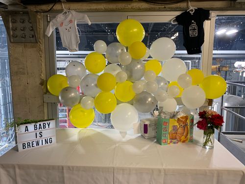 Event space at Rio Bravo Brewing featuring tables, folding chairs, string lights, and wooden barrels in the background.