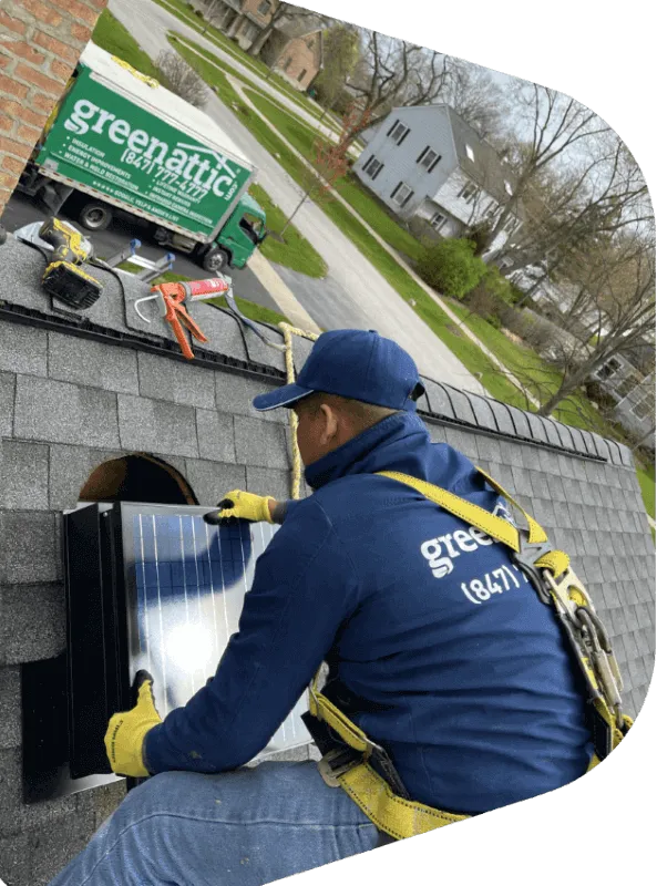 Green Attic technician mounting a solar attic fan on an asphalt shingle roof