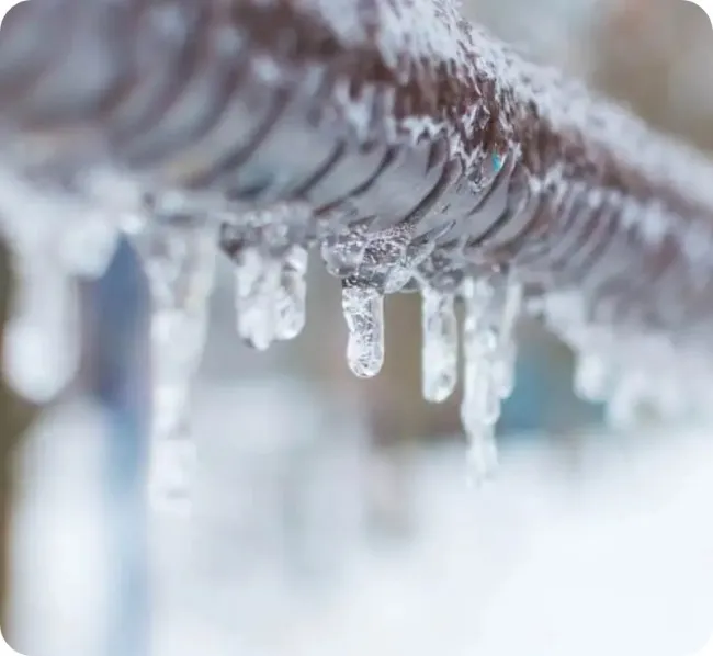 Close-up of a frozen metal pipe covered in icicles during winter
