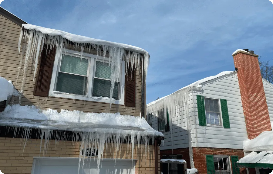 Large icicles along roof edge indicating an ice dam on a house