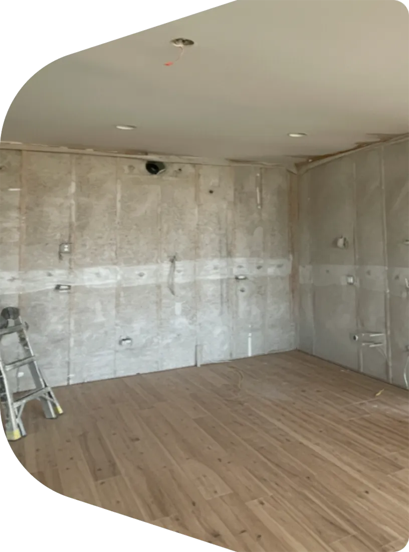 Basement wall prepared for insulation with exposed studs and moisture barrier installation in progress