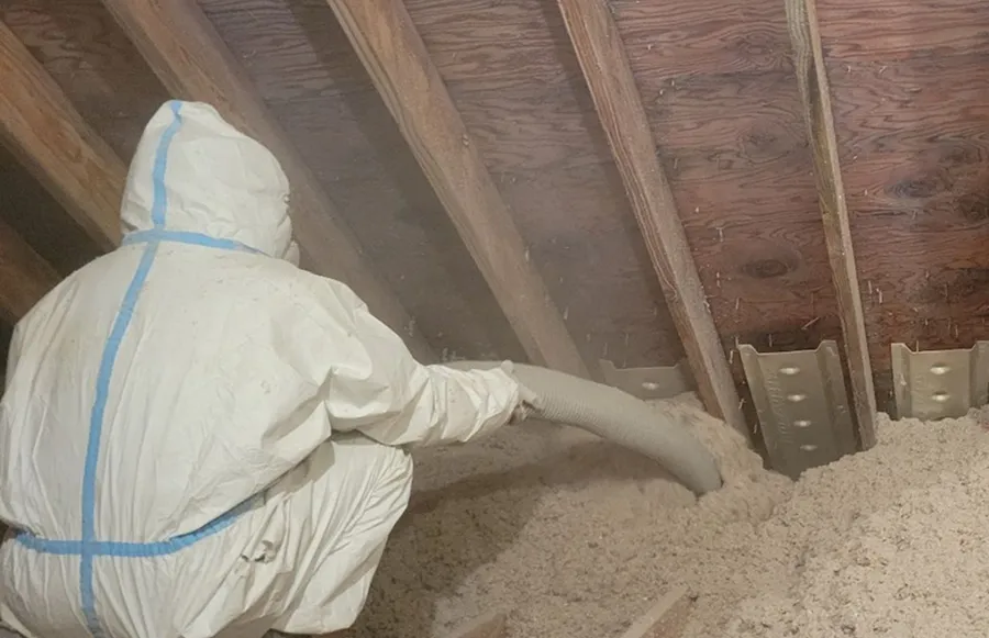 Technician installing eco-friendly blown-in cellulose insulation across an attic floor