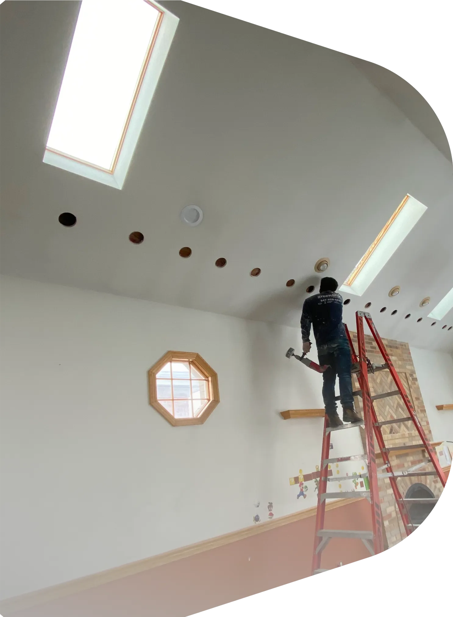 Installer preparing a cathedral ceiling for insulation with multiple ceiling cutouts and skylights visible