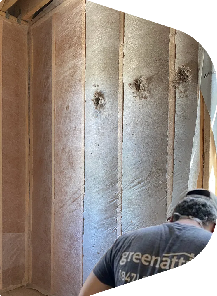 Green Attic technician dense-packing soundproof insulation into an interior wall cavity