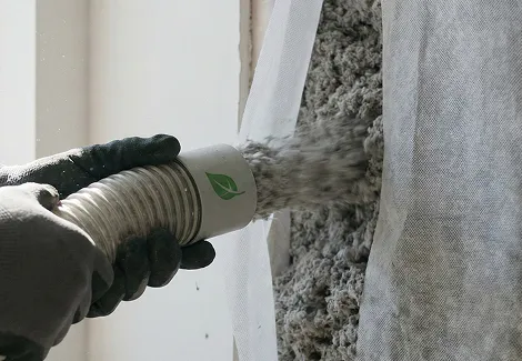 Installer blowing dense-pack cellulose insulation into a wall cavity