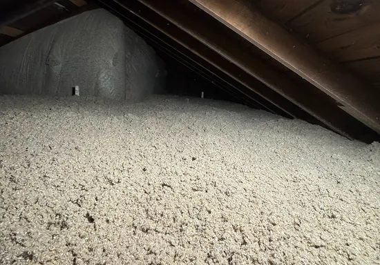 Attic filled with blown-in cellulose insulation covering the attic floor between joists