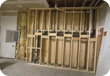 Framed basement wall with electrical and plumbing before insulation