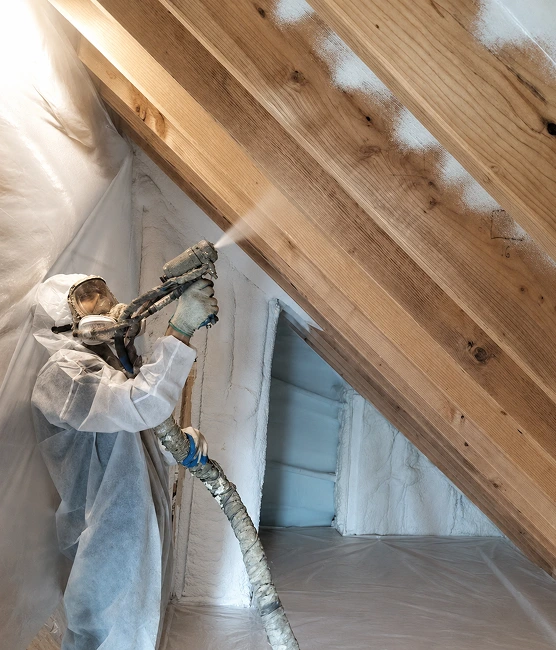 Technician applying spray foam insulation to the attic roof deck