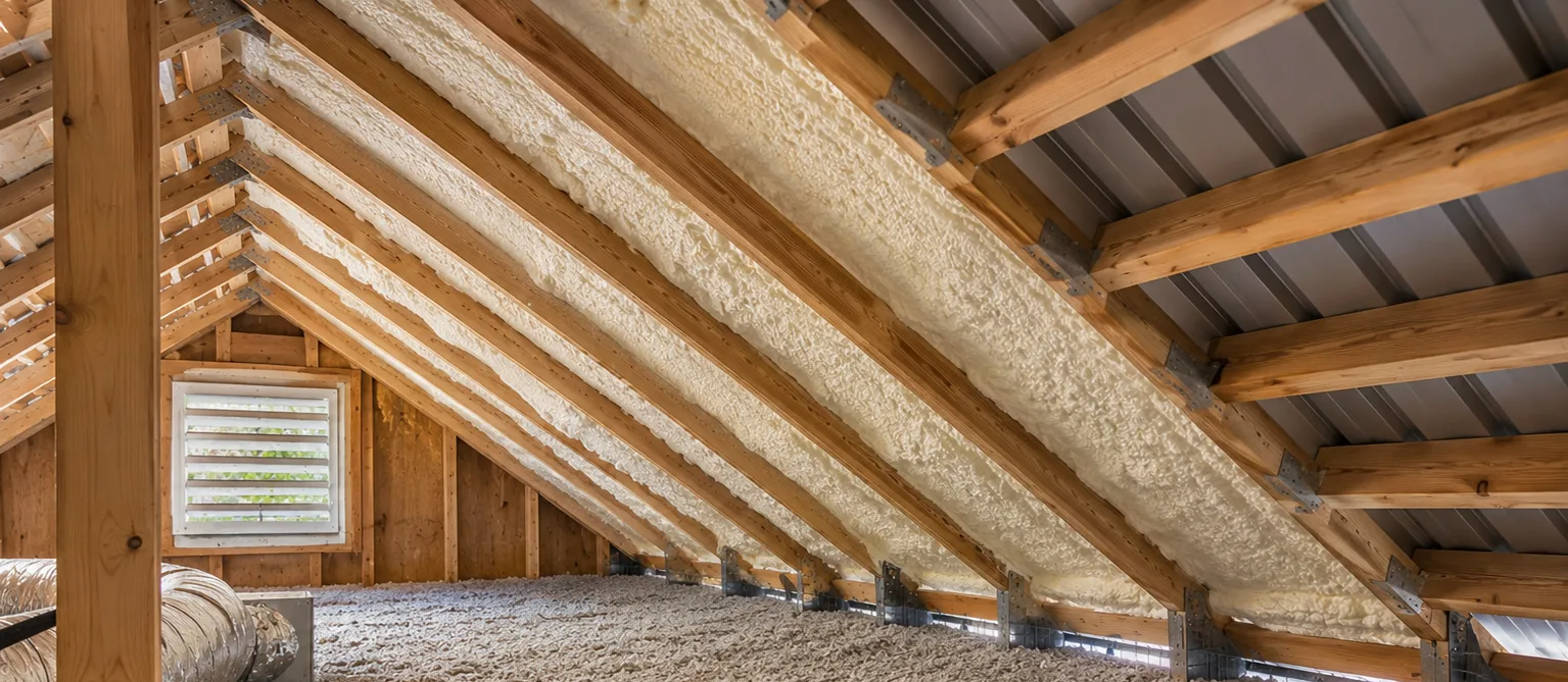 Residential metal roof insulation with spray foam along roof rafters and loose-fill insulation on the attic floor