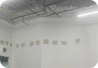 Finished commercial wall after cellulose insulation access holes were patched