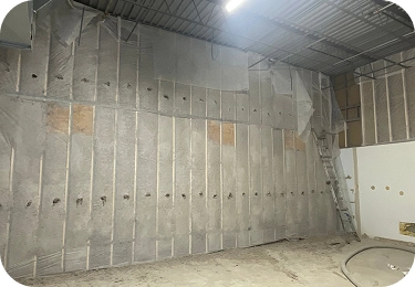 Dense-pack cellulose insulation installed across a tall commercial interior wall