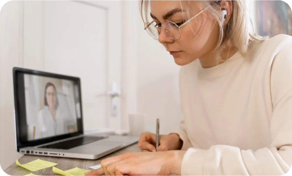 Femme suivant un cours en ligne et prenant des notes à son bureau