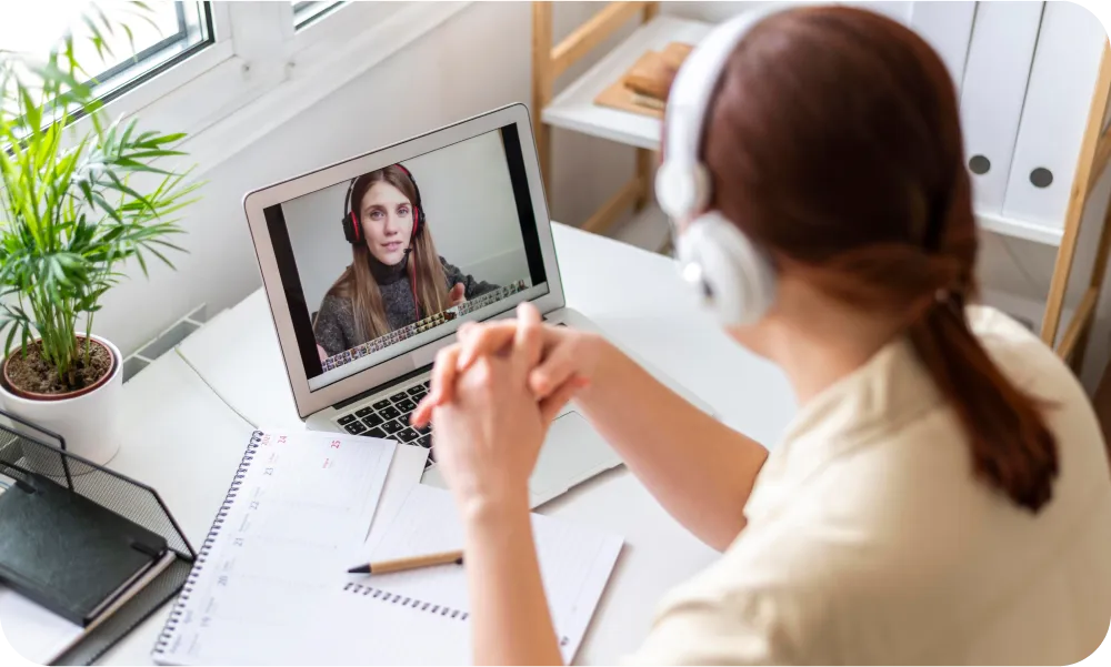 Femme en visioconférence avec un casque audio devant son ordinateur