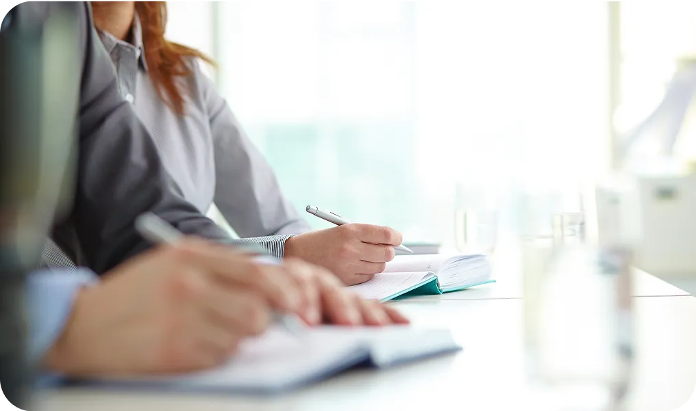 Femme prenant des notes dans un carnet lors d'une réunion professionnelle