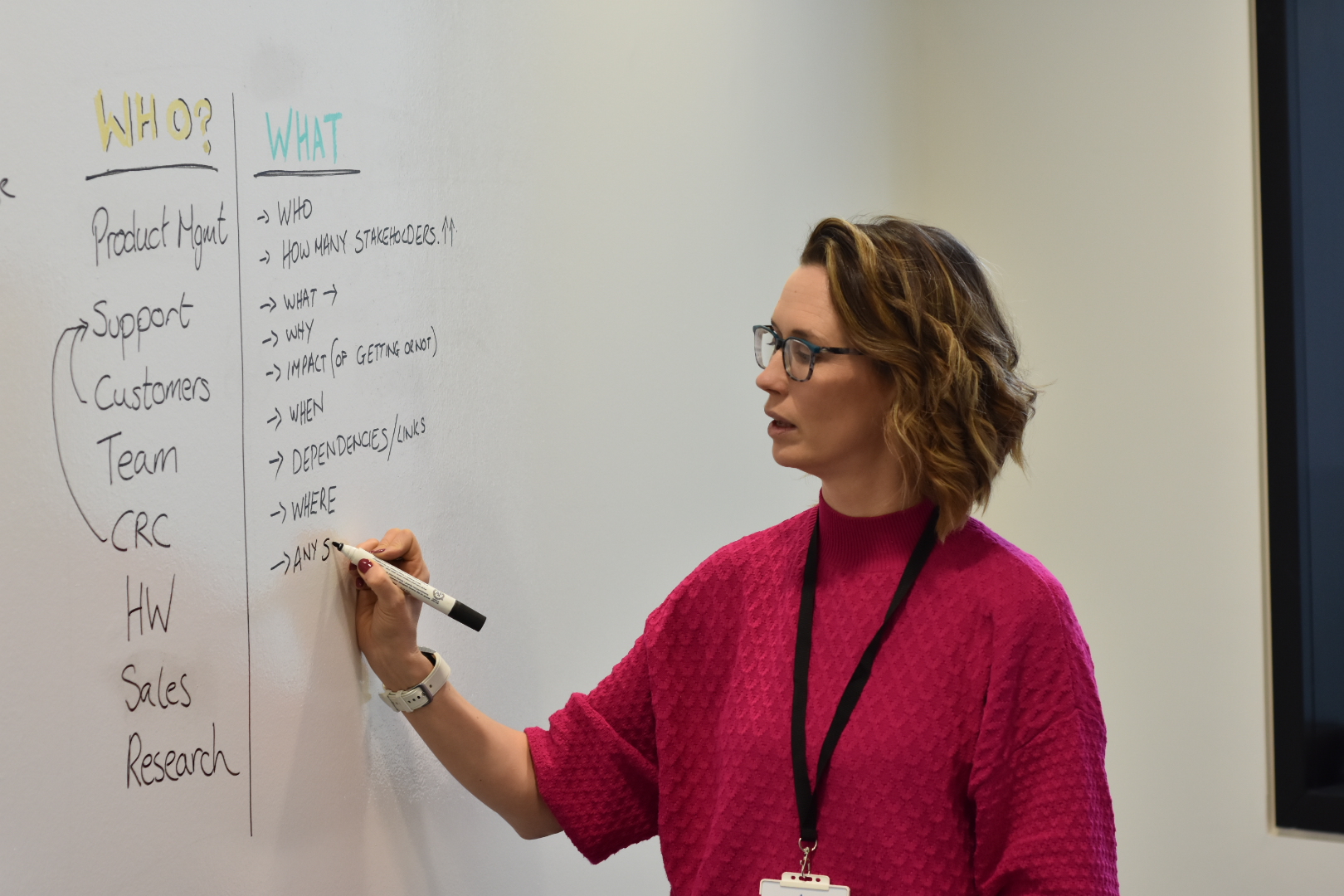 A woman writing on a white board with marker.
