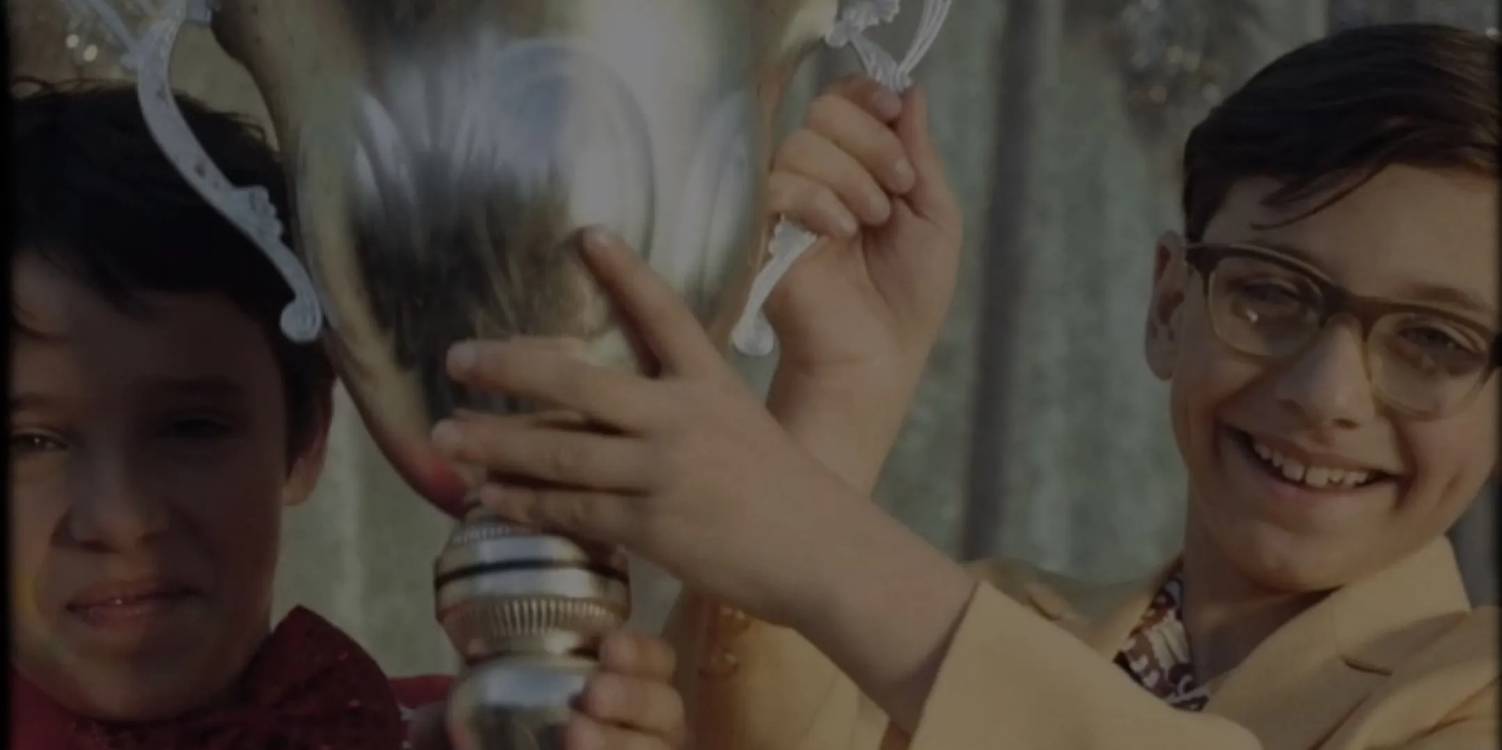 An image of the boy holding a trophy.