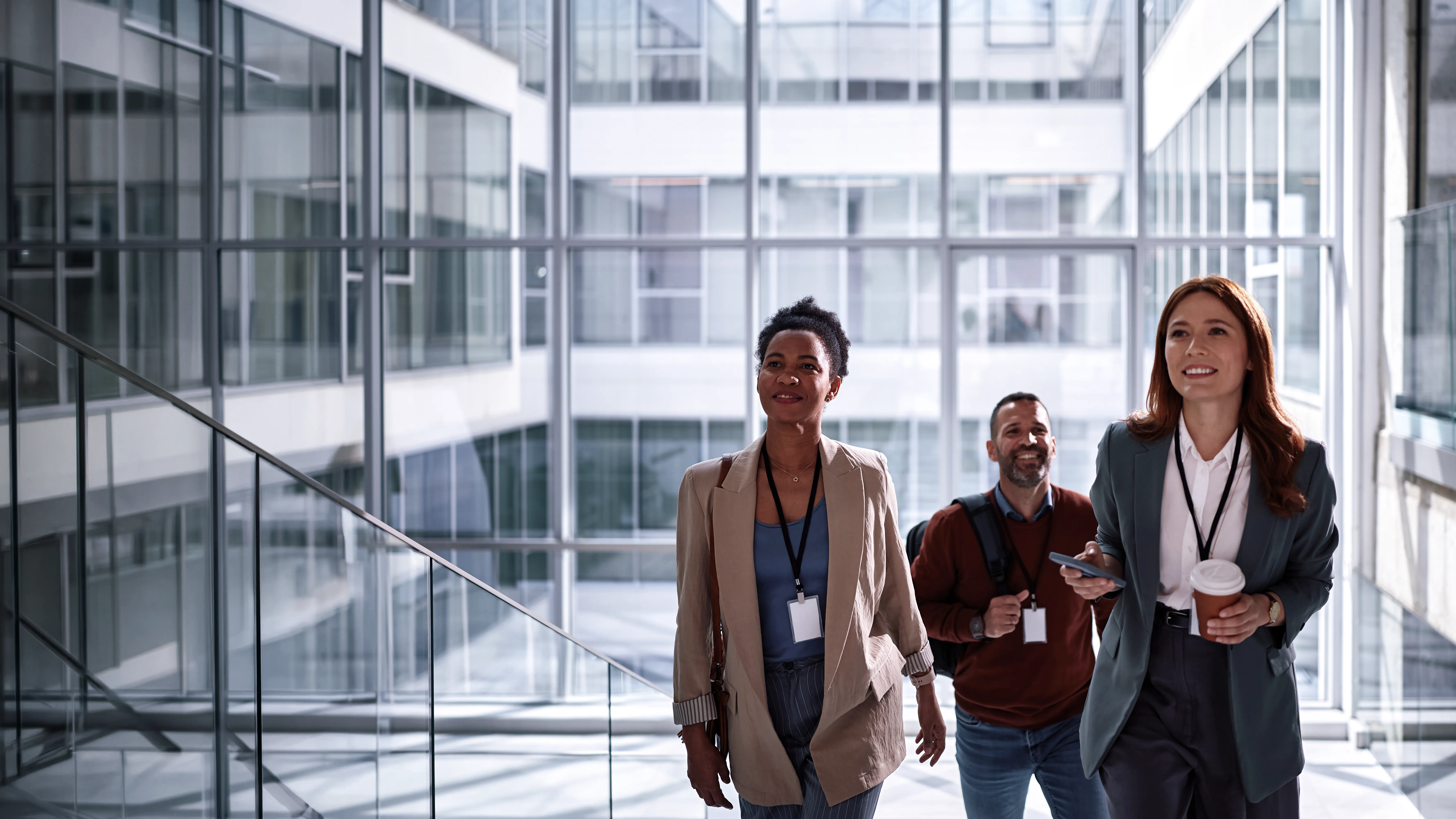 Three real estate professionals walking through an office building lobby