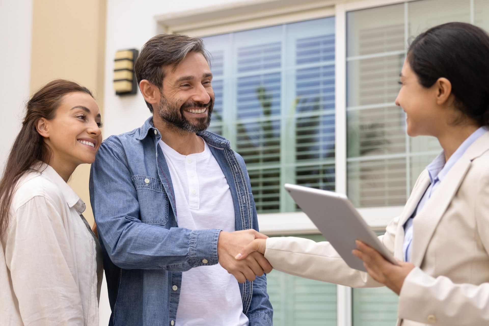 Real estate agent shaking hands with home buyers after closing, representing protection against buyer default and real estate commission risk in Canada