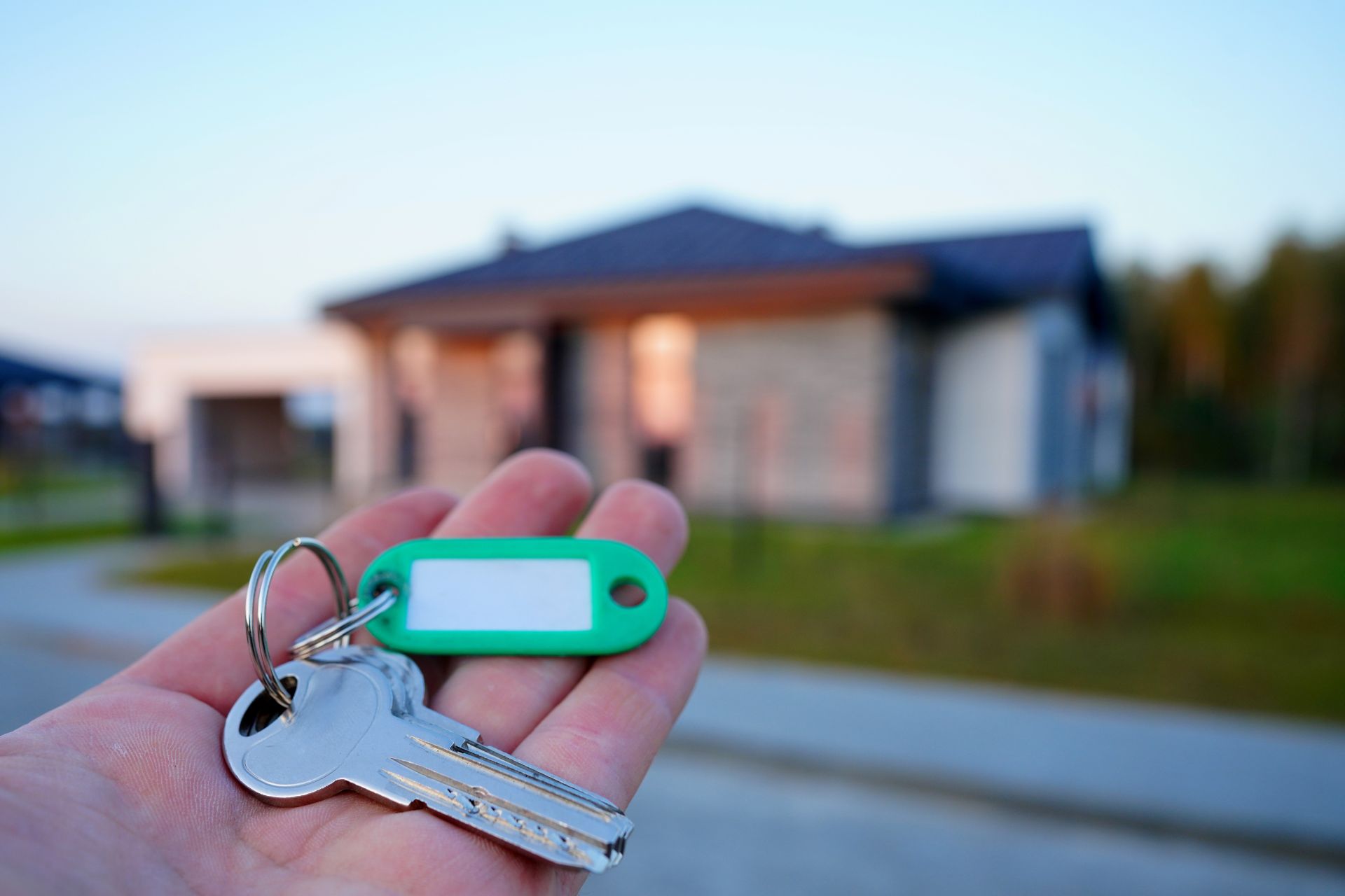 House keys in hand in front of a home, representing the difference between home closing insurance and title insurance