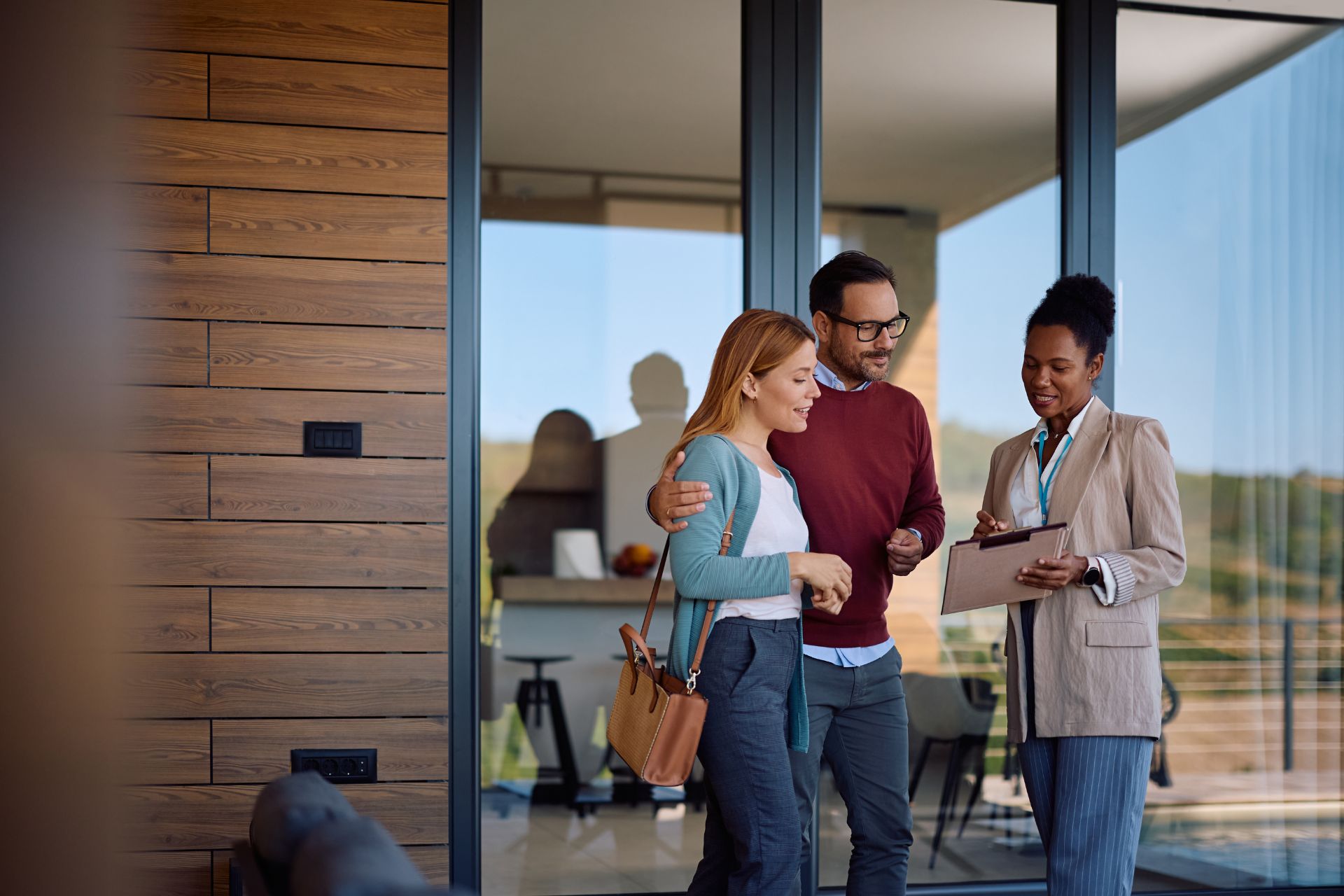 Real estate agent reviewing documents with clients outside a modern home, representing closing risk protection and client guidance