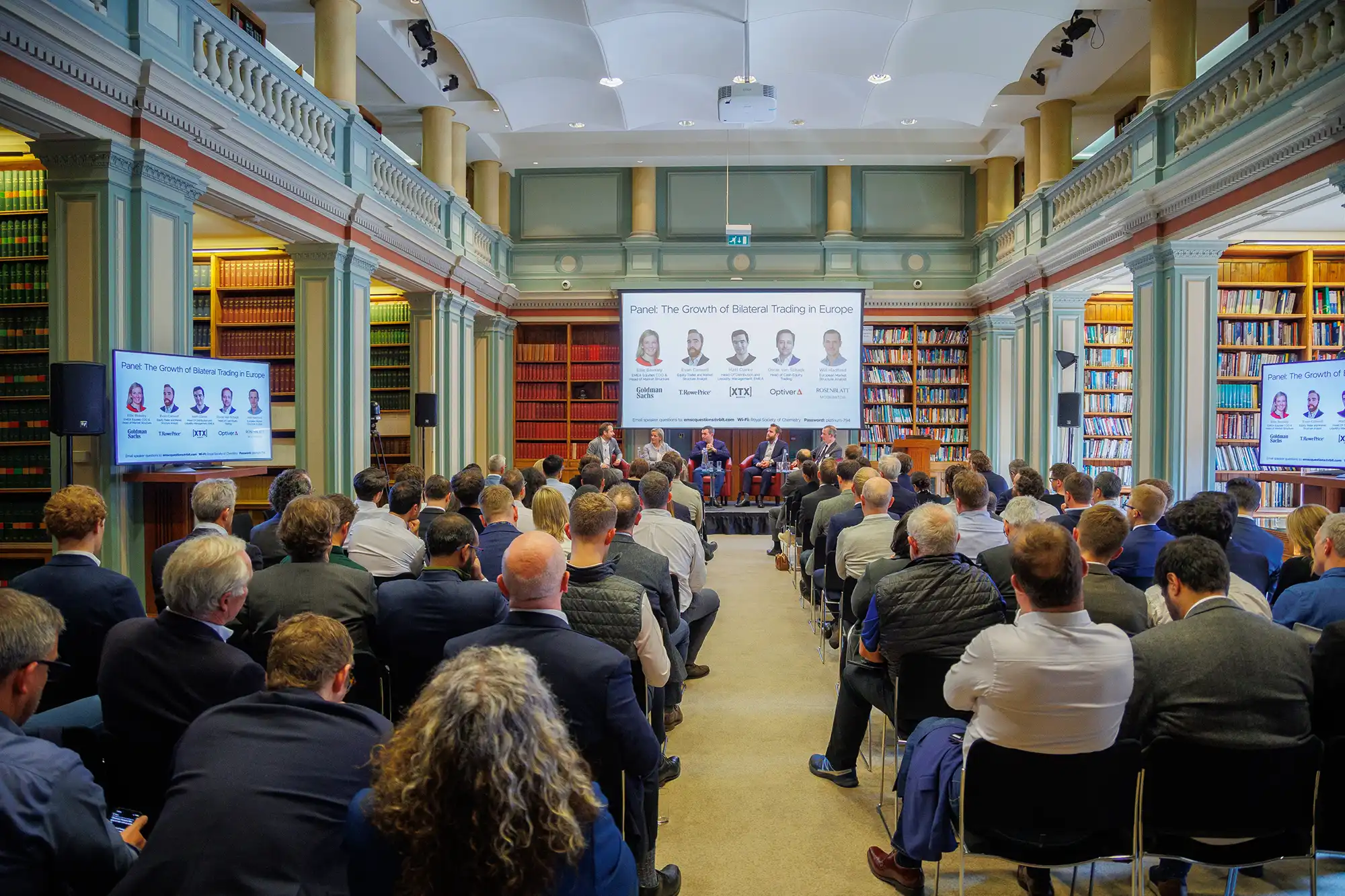 Wide shot of a panel titled The Growth of Bilateral Trading in Europe held at the Royal Society of Chemistry library with a seated audience and speakers.